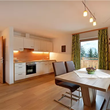 A modern kitchen with dining area and plenty of natural light. A beautiful view of nature is visible through the window.