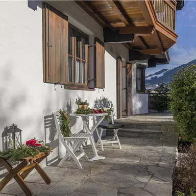 An inviting terrace with a small table and chairs. In the background, there are trees and mountains that emphasize the tranquil atmosphere.