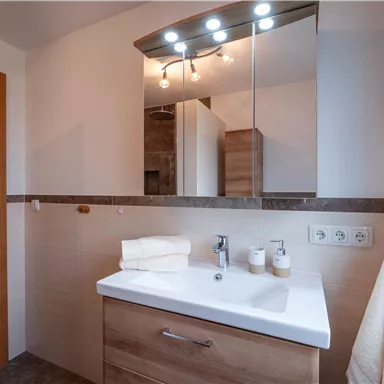 A modern bathroom with wooden paneling and a stylish sink. The lighting creates a pleasant atmosphere.