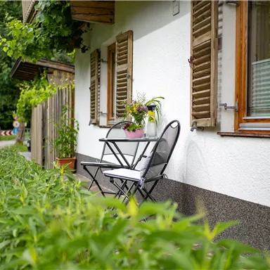 A cozy balcony with a small table and chairs.
Surrounded by green plants and a picturesque view of the street.