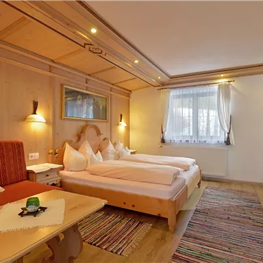 Ein gemütliches Zimmer mit Holzdekor und zwei Betten. Der Raum hat ein Fenster mit hellem Licht und einen kleinen Tisch mit einer Dekoration.