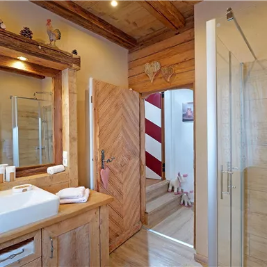 Ein modernes Badezimmer mit Holzdetails und einer Dusche. Der Raum ist hell und einladend gestaltet.