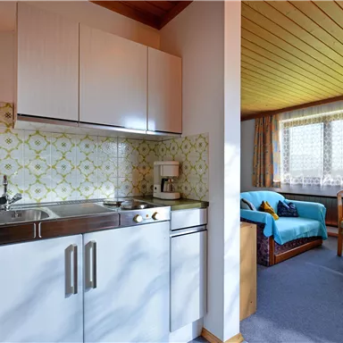 Eine gemütliche Unterkunft mit einer kleinen Küche und einem Wohnbereich. Helle Farben und viel Tageslicht schaffen eine einladende Atmosphäre.
