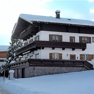Ein schönes Haus im Schnee mit einem überdachten Balkon. Die Umgebung ist winterlich und ruhig.