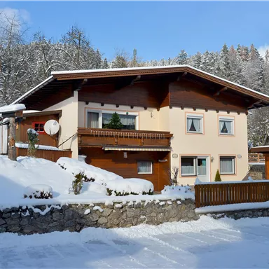 A charming house in the snow, surrounded by snow-covered trees. The landscape resembles an idyllic winter scenery.