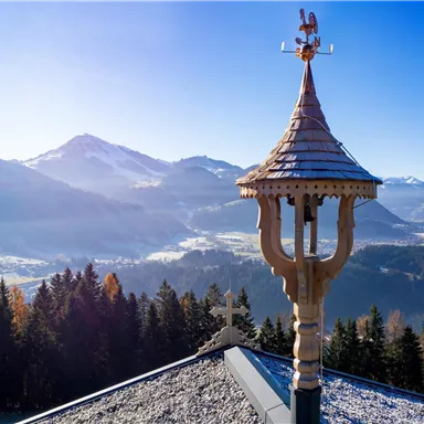 A beautiful view of the mountains and valleys. In the foreground, an artistically designed bell cote is visible.
