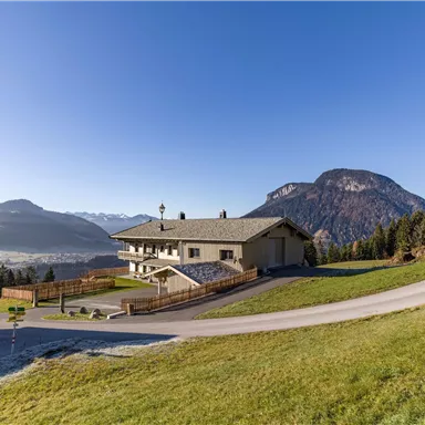 A modern house in a picturesque mountain landscape. The clear sky and the green meadows create an inviting atmosphere.
