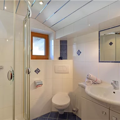 Ein modernes Badezimmer mit Dusche und großen Spiegelschränken. Helle Fliesen und ein Fenster sorgen für eine freundliche Atmosphäre.