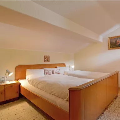 Ein gemütliches Schlafzimmer mit einem Doppelbett und Holzmöbeln. Sanfte Beleuchtung schafft eine einladende Atmosphäre.