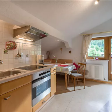 Eine moderne Küchenecke mit hellen Holzmöbeln und einem großen Fenster. Der Raum ist freundlich und einladend.