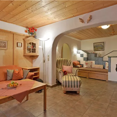 Ein gemütliches Wohnzimmer mit Holzverkleidung und schöner Beleuchtung. Es gibt eine Sitzecke mit einem Sofa und einem Sessel sowie einen Kamin.