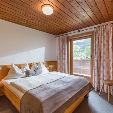 Ein gemütliches Schlafzimmer mit einem Holzdecke und einem großen Bett. Große Fenster bieten einen Blick auf die Natur draußen.