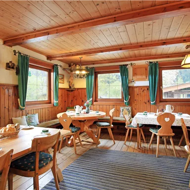 A cozy restaurant with wooden furniture and a green curtain. Tables are set, and the atmosphere is inviting.
