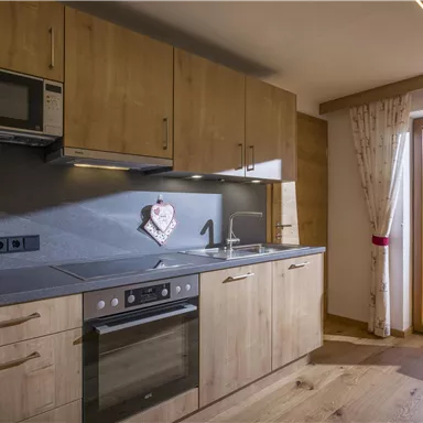 A modern kitchen with wooden cabinets and a window that shows a beautiful view. A coffee machine and a microwave are on the countertop.