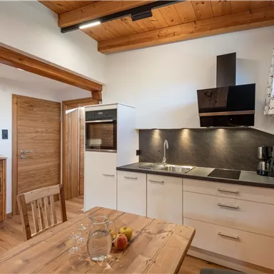 Eine moderne Küche mit Holzelementen und einer gemütlichen Esstischgruppe. Die Möbel sind hell und freundlich gestaltet.