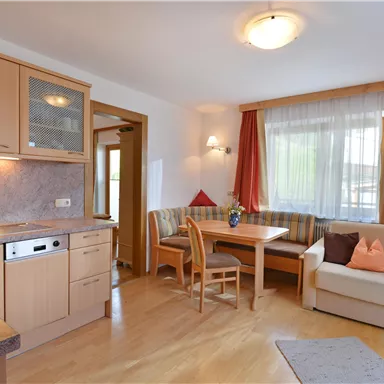 Eine helle und gemütliche Wohnung mit moderner Küchenausstattung. Der Wohnbereich ist freundlich eingerichtet und bietet Platz zum Entspannen und Essen.