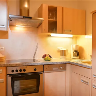 Eine moderne Küche mit Holzmöbeln und einem Herd. Sie ist gut ausgestattet mit modernen Geräten und hat eine gemütliche Atmosphäre.