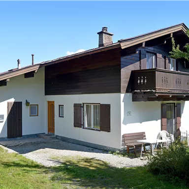 Ein gemütliches Haus mit Balkon in ländlicher Umgebung. Die Wiese ist grün und die Himmel ist klar.