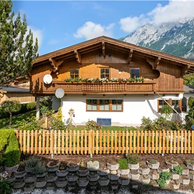 A traditional house with wooden cladding in a picturesque landscape.
Surrounded by a well-maintained garden and a view of the mountains.