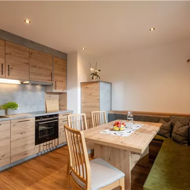 Eine moderne Küche mit Holzschränken und eleganten Elektrogeräten. Der Essbereich ist gemütlich mit einem Tisch und Stühlen eingerichtet.