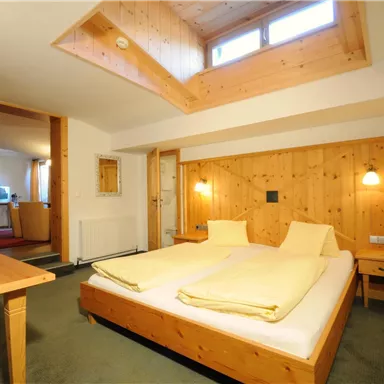 Ein gemütliches Schlafzimmer mit Holzdekor und zwei Betten. Der Raum hat natürliche Lichtquellen und eine einladende Atmosphäre.