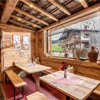 A cozy restaurant with wooden paneling and an inviting atmosphere. Through the large window, you can see the green landscape outside.