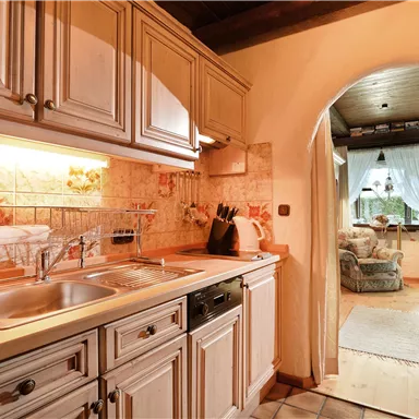 A modern kitchen with bright cabinets and a sink. In the background, an arch leads to a cozy living area.
