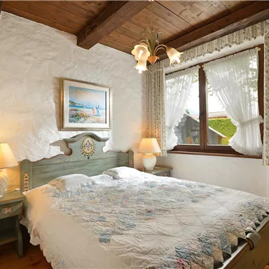 A cozy bedroom with a double bed and pleasant decoration. Large windows let in plenty of daylight.
