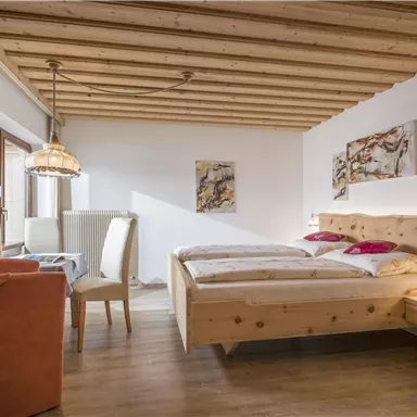 A cozy bedroom with wooden furniture and warm lighting. The decor is modern and inviting, ideal for relaxing overnight stays.