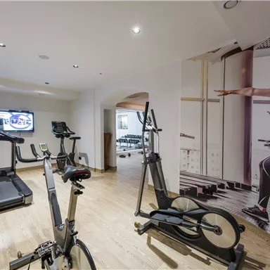 A modern gym with a treadmill, exercise bike, and a motif on the wall. The room is bright and inviting.