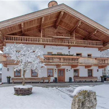 Ein traditionelles, Holzhaus im Winter mit Schnee bedeckt. Es hat einen großen Balkon und befindet sich in einer ruhigen, malerischen Umgebung.