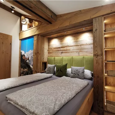 Ein gemütliches Schlafzimmer mit Holzdesign und einem großen Doppelbett. Die Wände sind mit warmen Tönen gestaltet und es gibt eine schöne Beleuchtung.