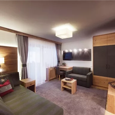 A modern living room with a cozy sofa, a table, and a television.
Wood paneling and soft lighting create an inviting atmosphere.