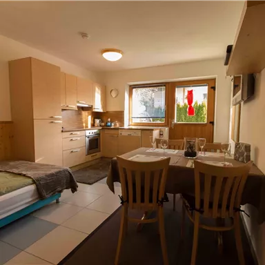 Eine gemütliche Küchen- und Wohnbereich mit Holzdekor. Ein Bett und ein Esstisch mit Stühlen sind ebenfalls vorhanden.