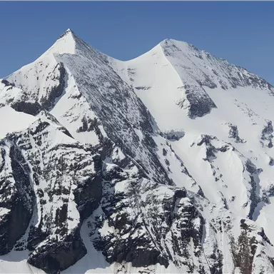 A majestic mountain panorama with snow-capped peaks. The clear blue sky makes the impressive landscape shine.