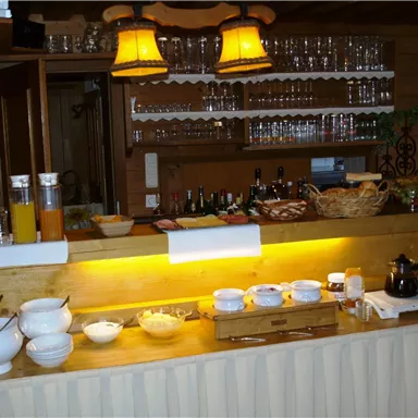 Eine einladende Frühstücksbar mit verschiedenen Schalen und Getränken. Im Hintergrund sind Gläser und Flaschen ordentlich aufgereiht.