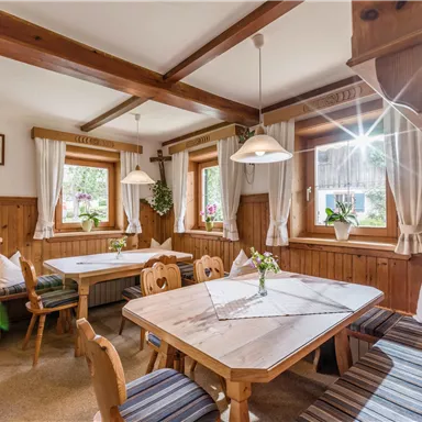 Ein einladendes Esszimmer mit Holzverkleidung und gemütlichen Sitzgelegenheiten. Das Licht strömt durch die Fenster und schafft eine warme Atmosphäre.