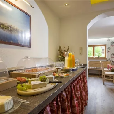 Ein einladendes Frühstücksbuffet mit verschiedenen Speisen und frischen Säften. Der Raum ist hell und gemütlich gestaltet.