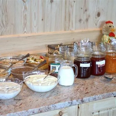 Ein Frühstücksbuffet mit verschiedenen Schüsseln. Es gibt Müsli, Joghurt, Marmelade und Nutella.