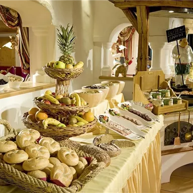 A lavish breakfast buffet with fresh rolls, fruit, and various dishes. The presentation is inviting and tasteful.