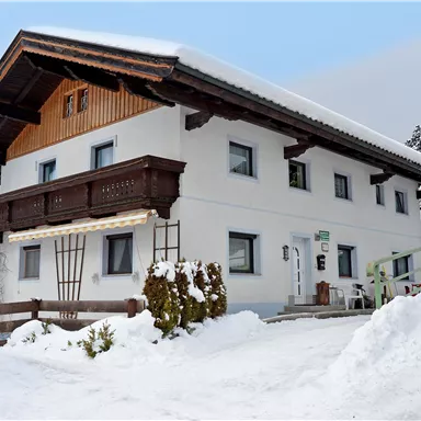 A charming house in the snow with a wooden balcony. The surroundings are wintry and picturesque.