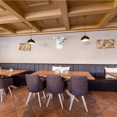 Ein modernes Restaurant mit Holztischen und eleganten Stühlen. Die Wände sind geschmackvoll dekoriert und es gibt gemütliche Sitzbereiche.