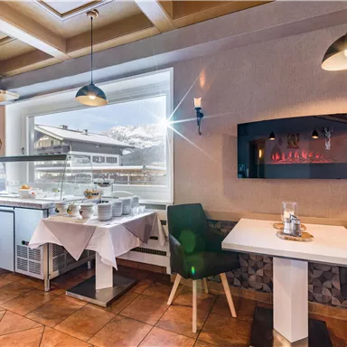 Ein einladendes Restaurant mit hellen Farben und modernem Design. Am Fenster sieht man eine schöne Aussicht auf die Berge.