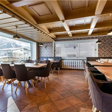 Ein gemütliches Restaurant mit Holzdekor und großen Fenstern. Die Einrichtung umfasst Tische und Stühle für eine einladende Atmosphäre.