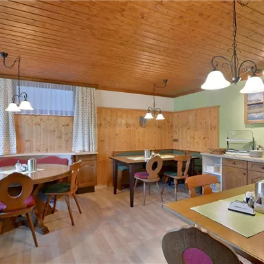 Ein gemütlicher Essbereich mit Holzwänden und Tischen. Der Raum ist hell erleuchtet und hat eine warme Atmosphäre.