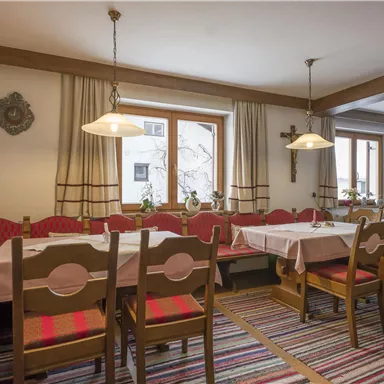 A cozy dining room with a large table and wooden benches. The windows are bright and let in plenty of light.