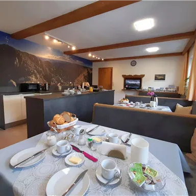 An inviting breakfast area with a table set for breakfast. In the background, a modern kitchen is visible.