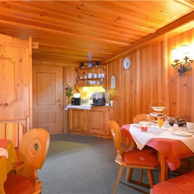 A cozy room with wooden paneling and warm light. Tables are set, and the room feels inviting.