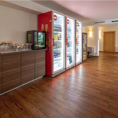 Ein gemütlicher Raum mit Holzfußboden und Kühlschränken, die Snacks und Getränke anbieten. Die Atmosphäre ist hell und einladend.