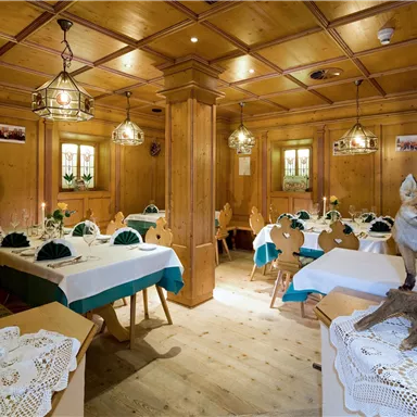 Ein rustikales Restaurant mit Holzwänden und liebevoll dekorierten Tischen. Ein Fuchs steht auf einem Regal und verleiht dem Raum eine besondere Atmosphäre.